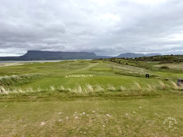 A close view of a flagstick at Rosses Point, with the Atlantic behind the green.