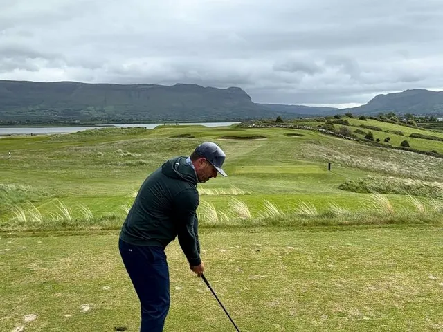 A fairway at County Sligo bending toward the water, with Benbulbin in the distance.