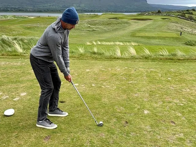 A golfer hitting a shot from the dunes at Rosses Point, with the bay ahead.