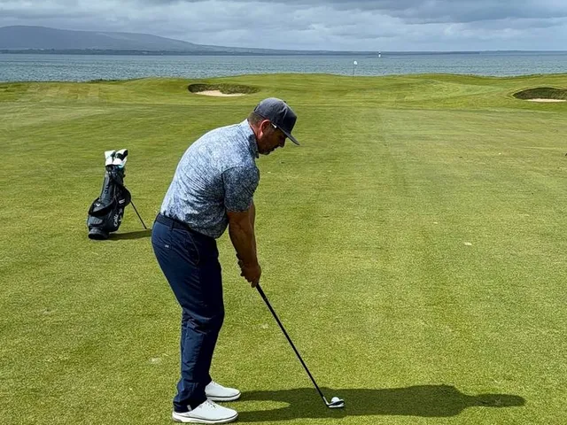 A green and flagstick at Rosses Point beside the dunes, with the bay beyond.
