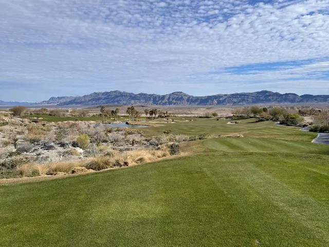A golfer hitting a shot at Coyote Springs, with the desert and the mountains ahead.