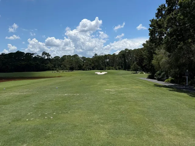 A green and flagstick at Magnolia, with a pond in front, a sand bunker beside the green, and a small waterfall.
