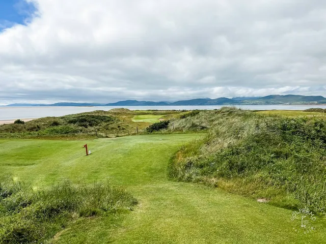 A green and flagstick at Dooks, with a bunker in front and the water behind the hole.