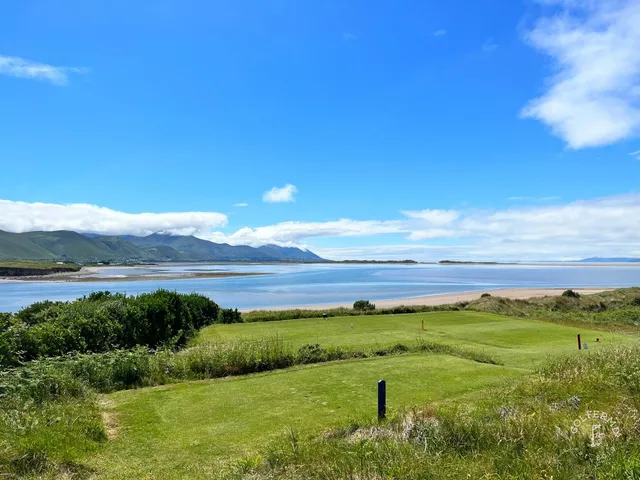 Golfers on a tee at Dooks, with the mountains across the water.