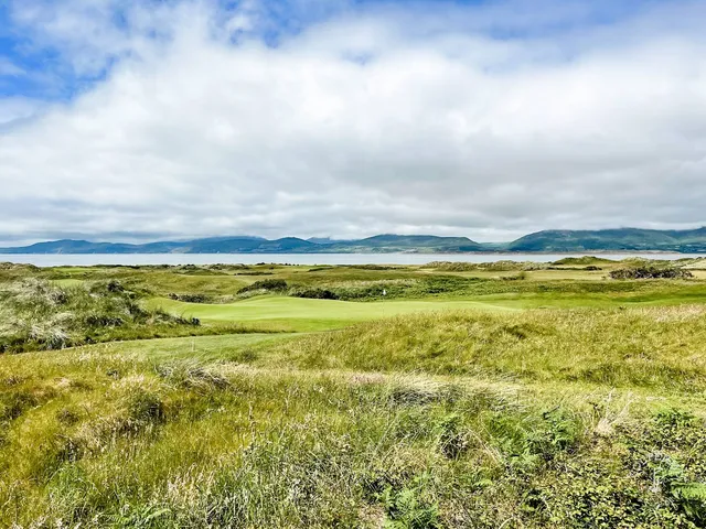 A golfer putting on a green at Dooks, with the bay beyond the hole.