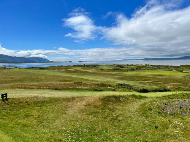 A close view of a flagstick at Dooks, with the water behind the green.