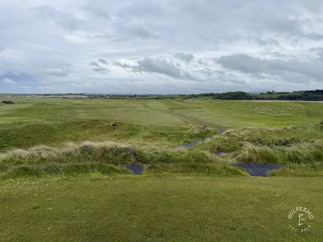 A green and flagstick at Enniscrone, with a bunker in front and the ocean behind the hole.