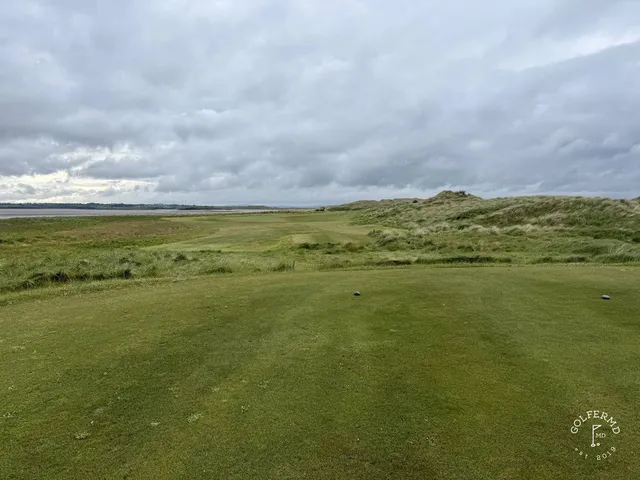 A golfer hitting a shot at Enniscrone, with the fairway and the water ahead.