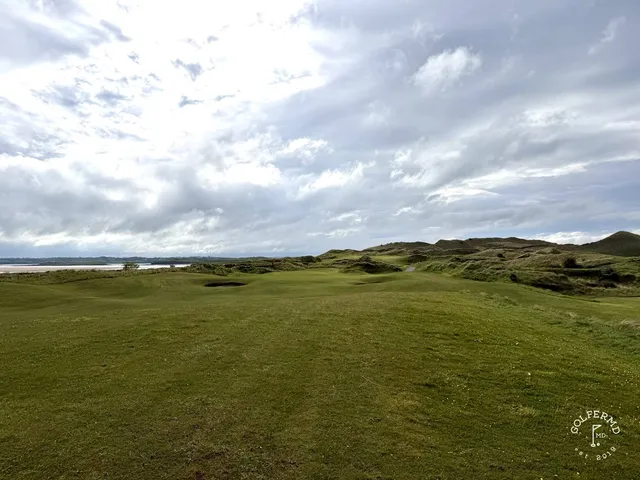A close view of a green and flagstick at Enniscrone, with the water behind it.
