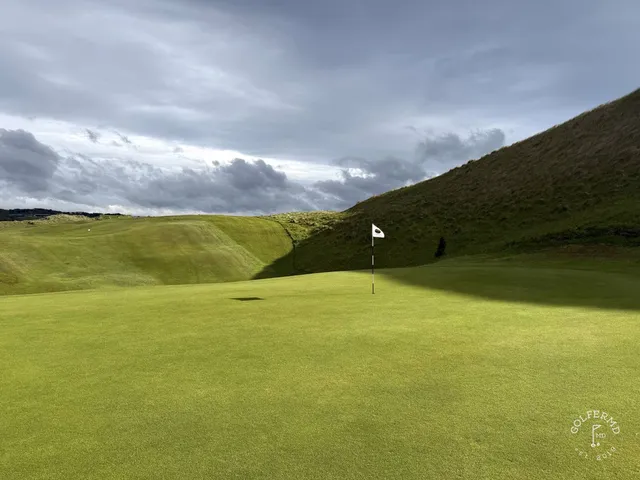 A fairway and green at Enniscrone, with a bunker in the foreground and the ocean beyond.