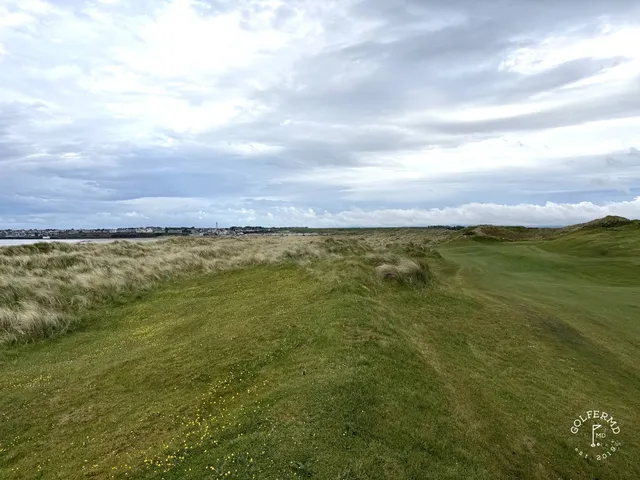 A green and flagstick at Enniscrone, seen from a rise, with the Atlantic behind the hole.