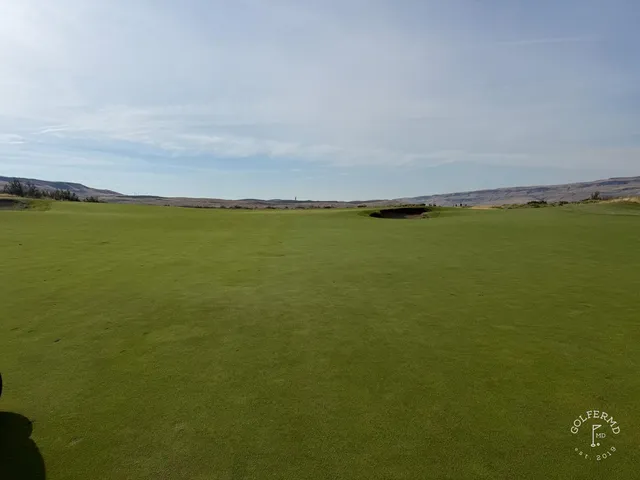 An elevated tee at Gamble Sands, a large bunker on the left and the green in the distance against the mountains.