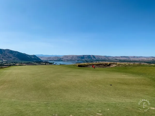 A green and flagstick at Gamble Sands, sandy ground in front of the hole and the fairway running back.