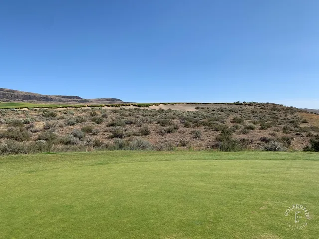 A bending fairway at Gamble Sands, with a bunker on the right and the mountains behind the green.