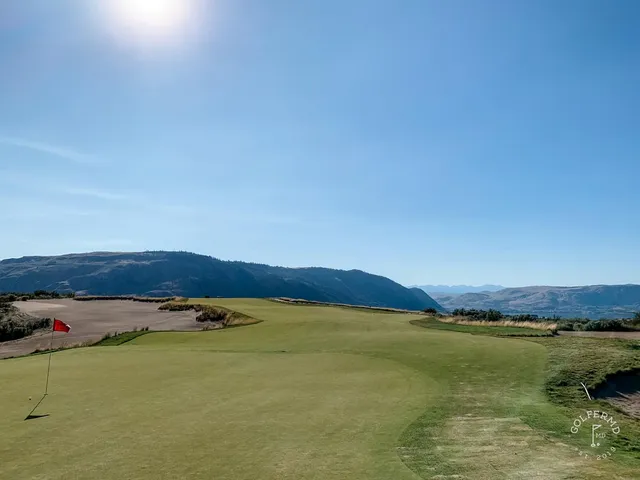 An elevated view at Gamble Sands, a broad sandy waste on the left and the green toward the mountains.