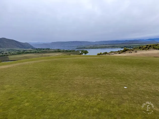 A panorama of several holes at Gamble Sands, sandy waste between the fairways and the mountains on the horizon.