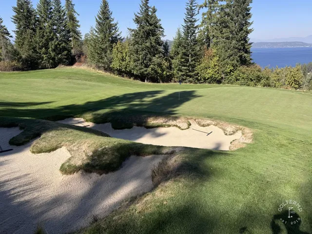 A green and flagstick at Gozzer Ranch, with a sand bunker and the lake behind the hole.