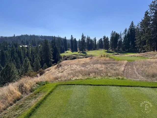 Golfers on a tee at Gozzer Ranch, with the lake and mountains behind them.