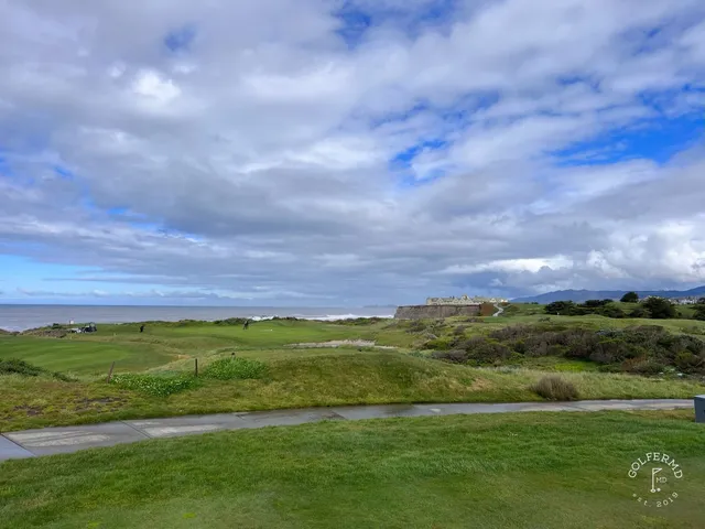 A green and flagstick on the bluff at Half Moon Bay Golf Links Ocean Course, with the ocean below.