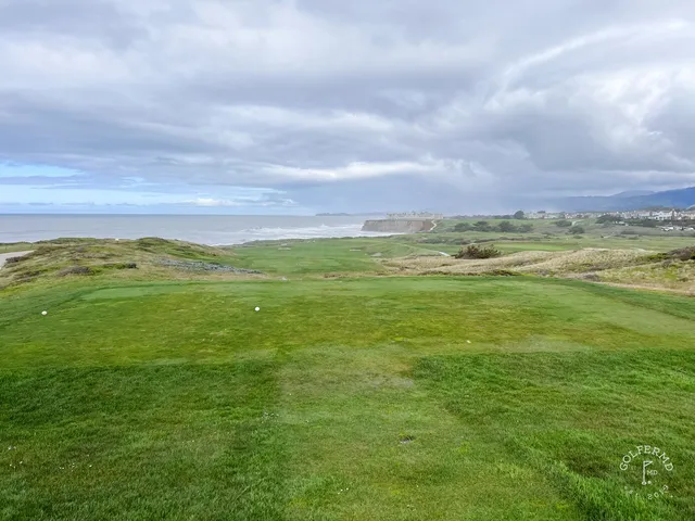 A fairway running toward the ocean at Half Moon Bay Golf Links Ocean Course, with cypress trees along the hole.