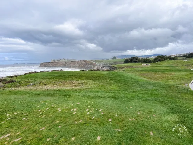 A green and flagstick above the ocean at Half Moon Bay Golf Links Ocean Course, with a bunker in front.
