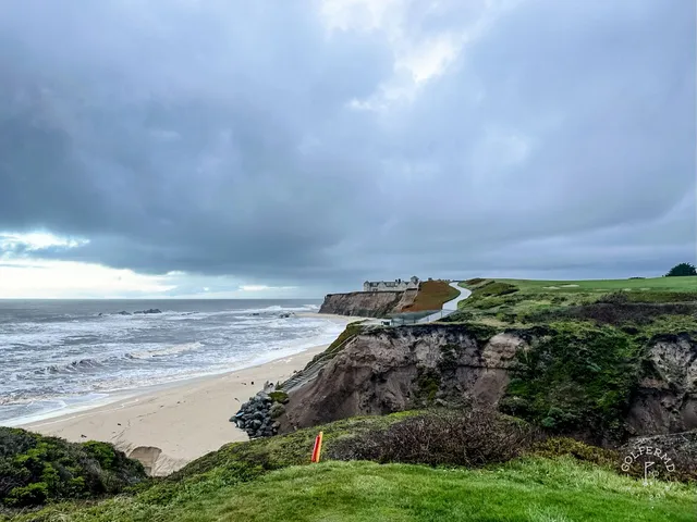 A golfer playing a shot from the rough at Half Moon Bay Golf Links Ocean Course, with the ocean behind the hole.