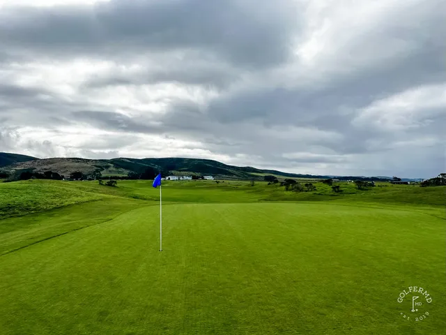 A golfer hitting a fairway shot at Half Moon Bay Golf Links Ocean Course, with the ocean behind the shot.