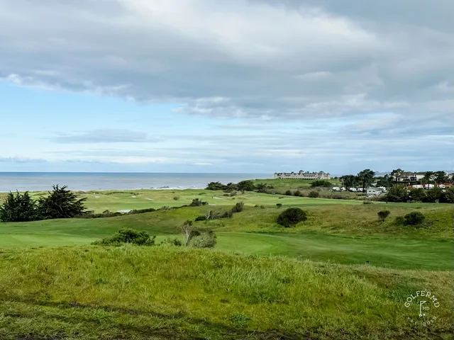 A golfer chipping toward a green at Half Moon Bay Golf Links Ocean Course, with the ocean behind the shot.