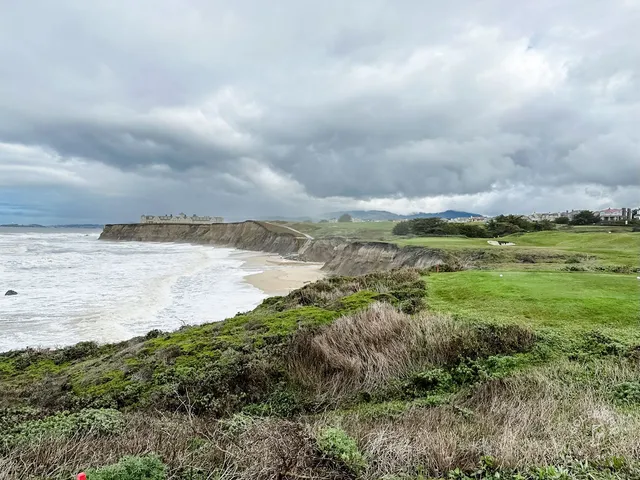 A golfer putting on a green above the ocean at Half Moon Bay Golf Links Ocean Course.