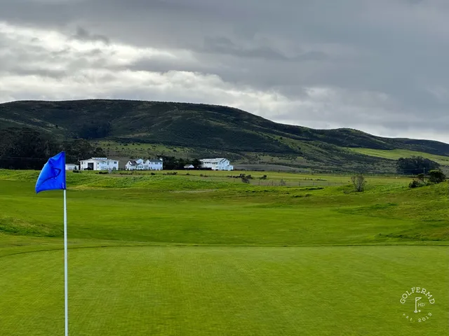 A green and flagstick on the bluff at Half Moon Bay Golf Links Ocean Course, with the ocean below.