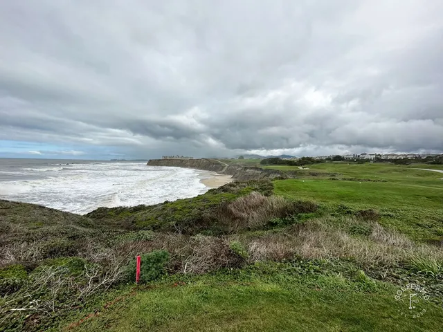 A fairway toward the ocean at Half Moon Bay Golf Links Ocean Course, with cypress trees along the hole.