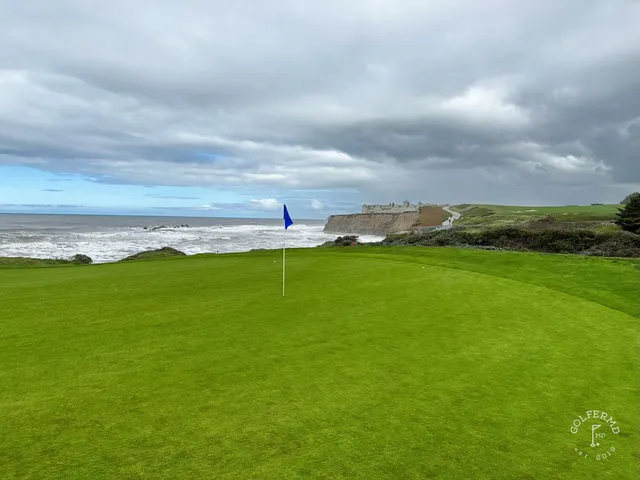 A green and flagstick on the edge of the bluff at Half Moon Bay Golf Links Ocean Course, with the ocean below.