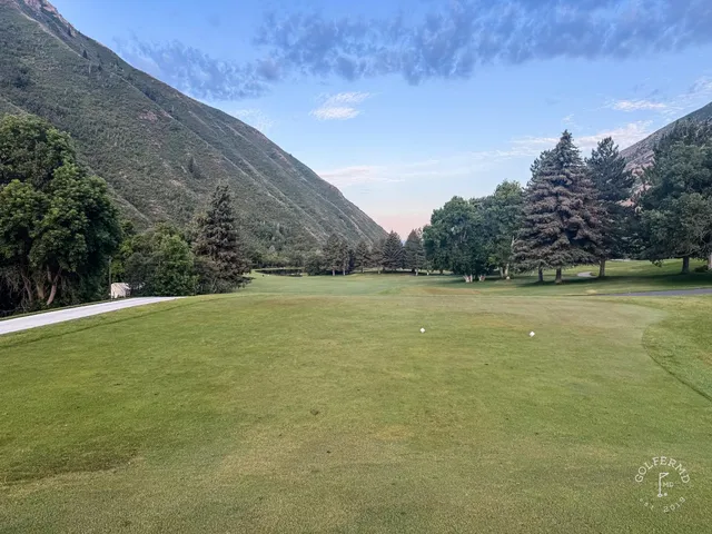 A fairway at Hobble Creek running toward the green, with trees on both sides and the mountains behind.
