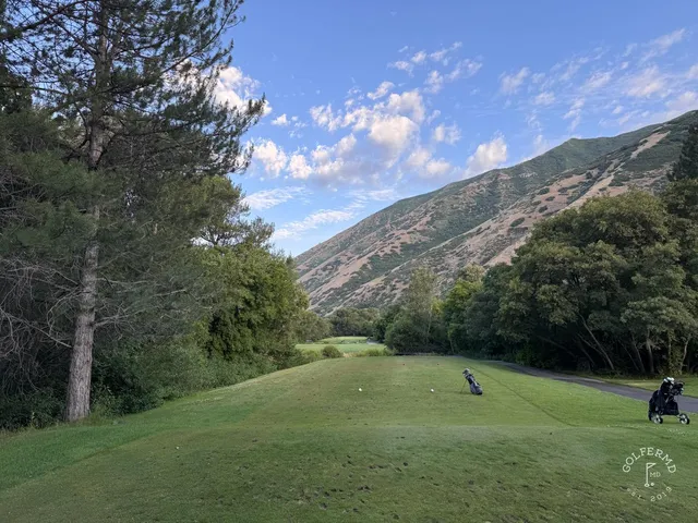 A green and flagstick at Hobble Creek, trees behind the hole and the mountains filling the background.