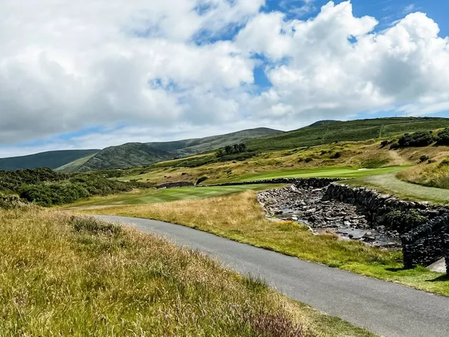 A green and flagstick at Hogs Head, with a bunker in front and the ocean behind the hole.