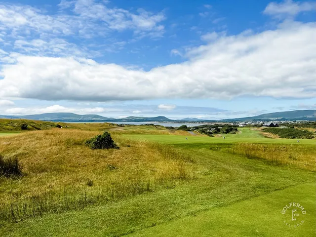 A golfer hitting a shot at Hogs Head, with the water ahead.