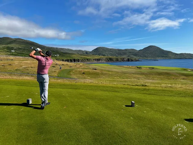 A close view of a flagstick at Hogs Head, with the bay behind the green.