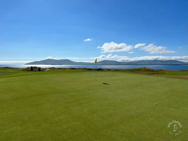 A golfer hitting a shot from the dunes at Hogs Head, with the ocean ahead.