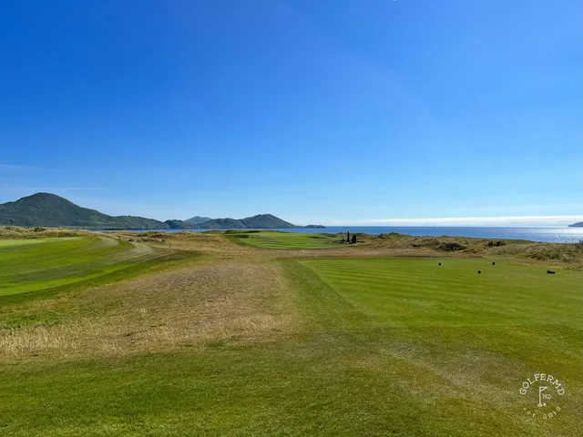 A close view of a flagstick at Hogs Head, with the mountains across the bay.