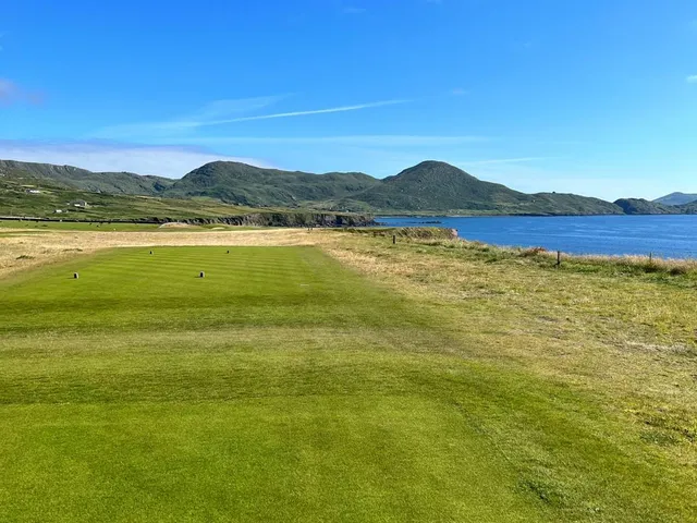 Golfers on a tee at Hogs Head, with the dunes and the water behind them.