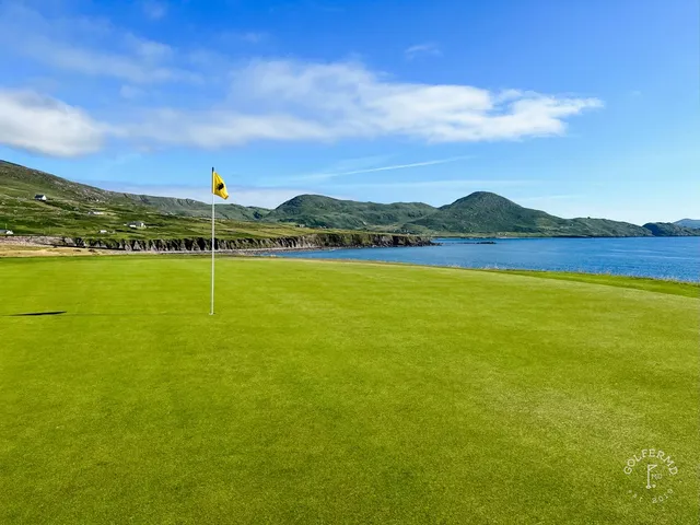 A green and flagstick at Hogs Head, with a bunker in front and the bay behind the hole.