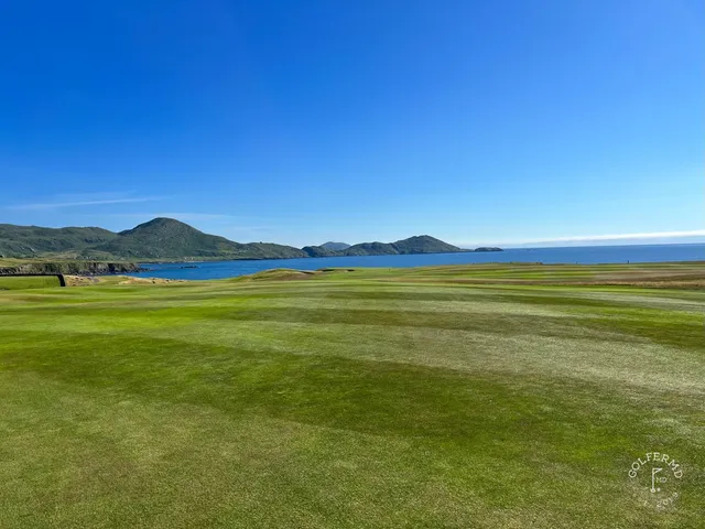 A close view of a flagstick at Hogs Head, with the ocean behind the green.