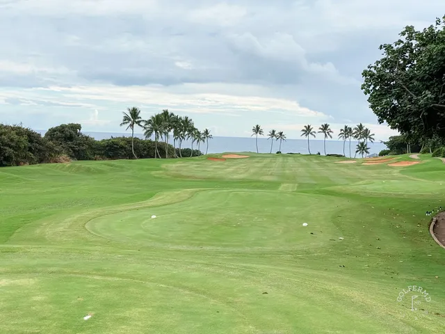 A green and flagstick at the Ocean Course, with the Pacific and a rocky shore behind the hole.