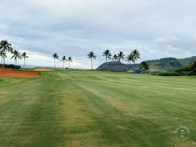A wide view at Hōkūala, with sand bunkers, palm trees, and the ocean on the horizon.