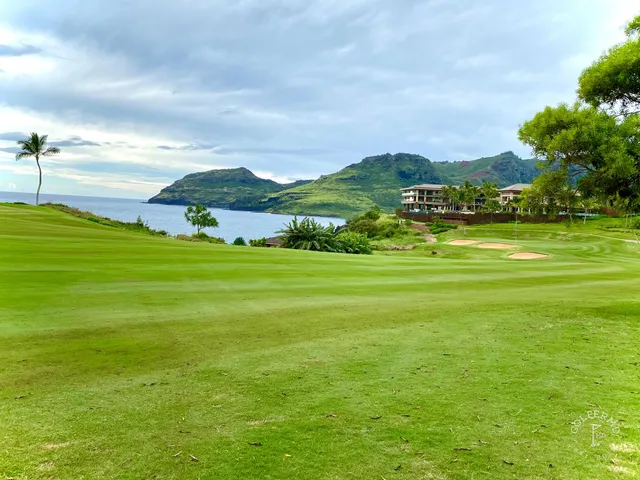 A fairway and green at Hōkūala, with a pond and palm trees beside the hole.