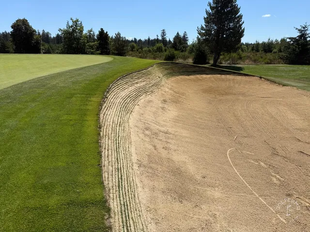 A golfer hitting a shot at The Home Course, with the fairway ahead.