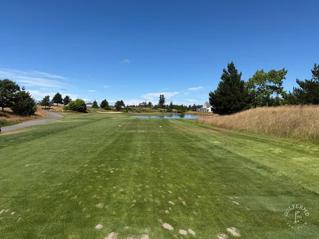 A fairway at The Home Course with a bunker along one side and trees beyond.