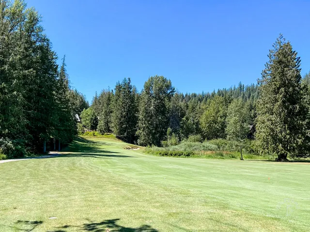 A fairway at The Idaho Club running through pines toward the lake.