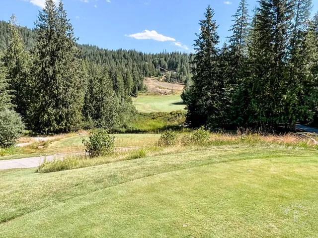 A wide view at The Idaho Club, with sand bunkers, pines, and the lake on the horizon.