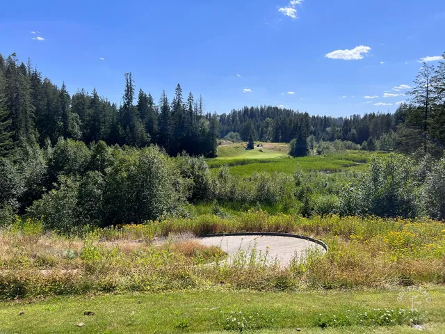 A golfer hitting a shot at The Idaho Club, with the fairway and lake ahead.
